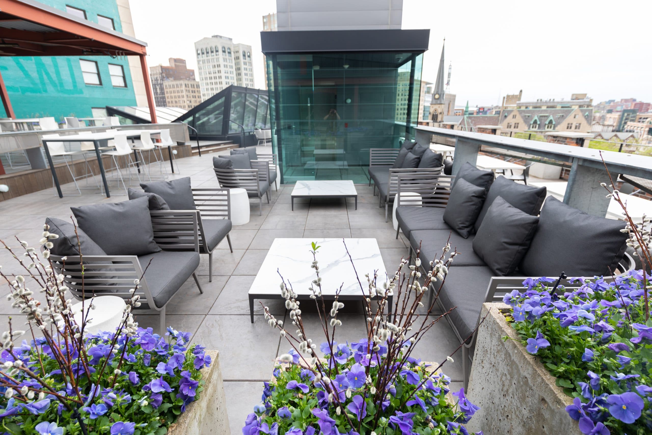 Furniture grouping with two coffee tables and live planters near elevator bank on The Madison Rooftop in Detroit.