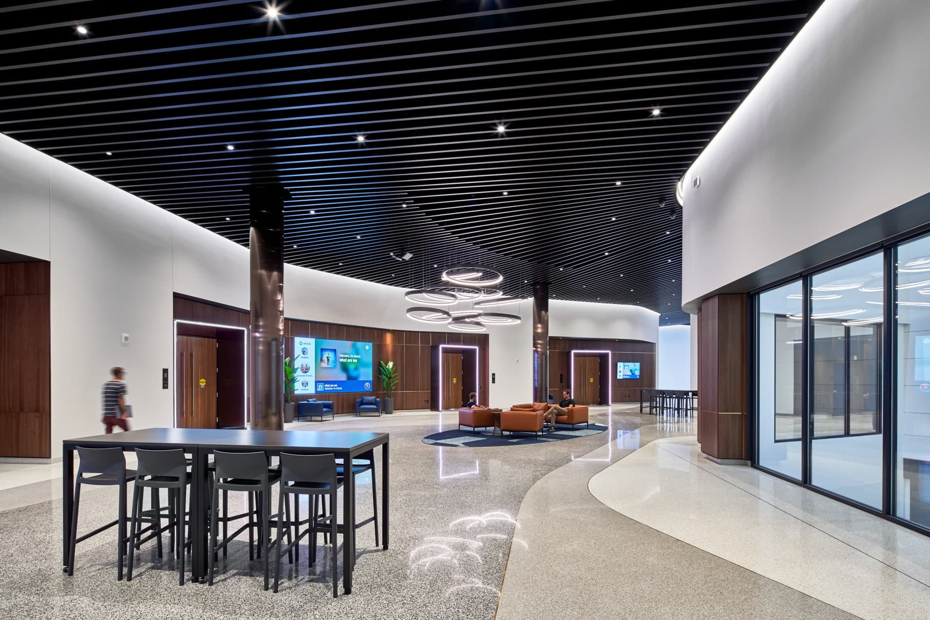 Pre-function lobby space of Elevate at One Campus Martius set with furniture group and communal tables and large circular chandelier in the center.